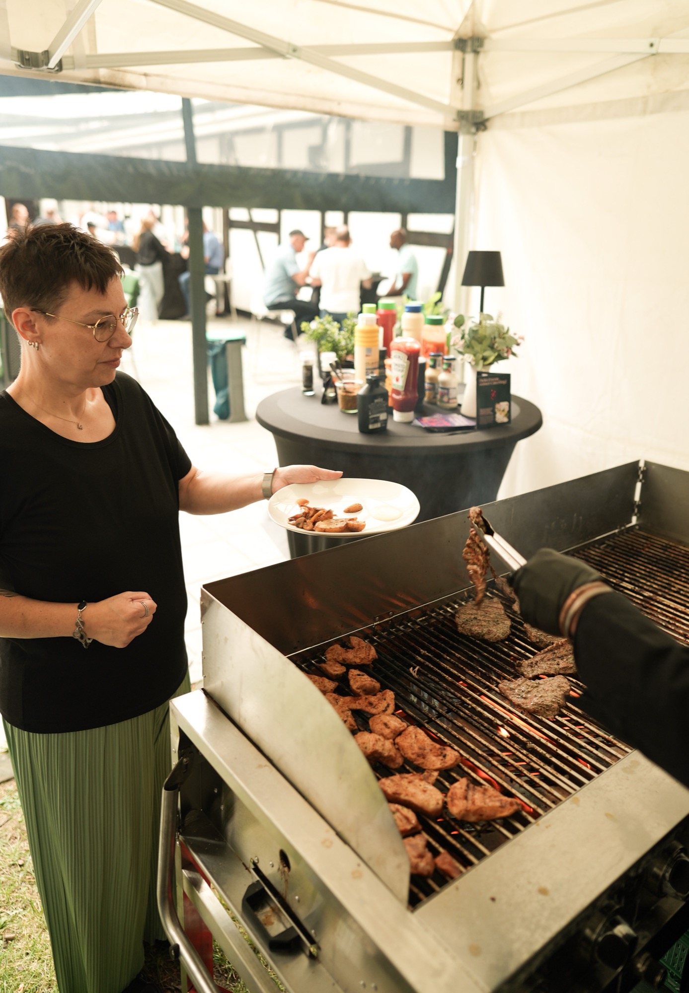 Grillmeister wendet Fleisch live auf der Grillstation bei einem Sommerfest