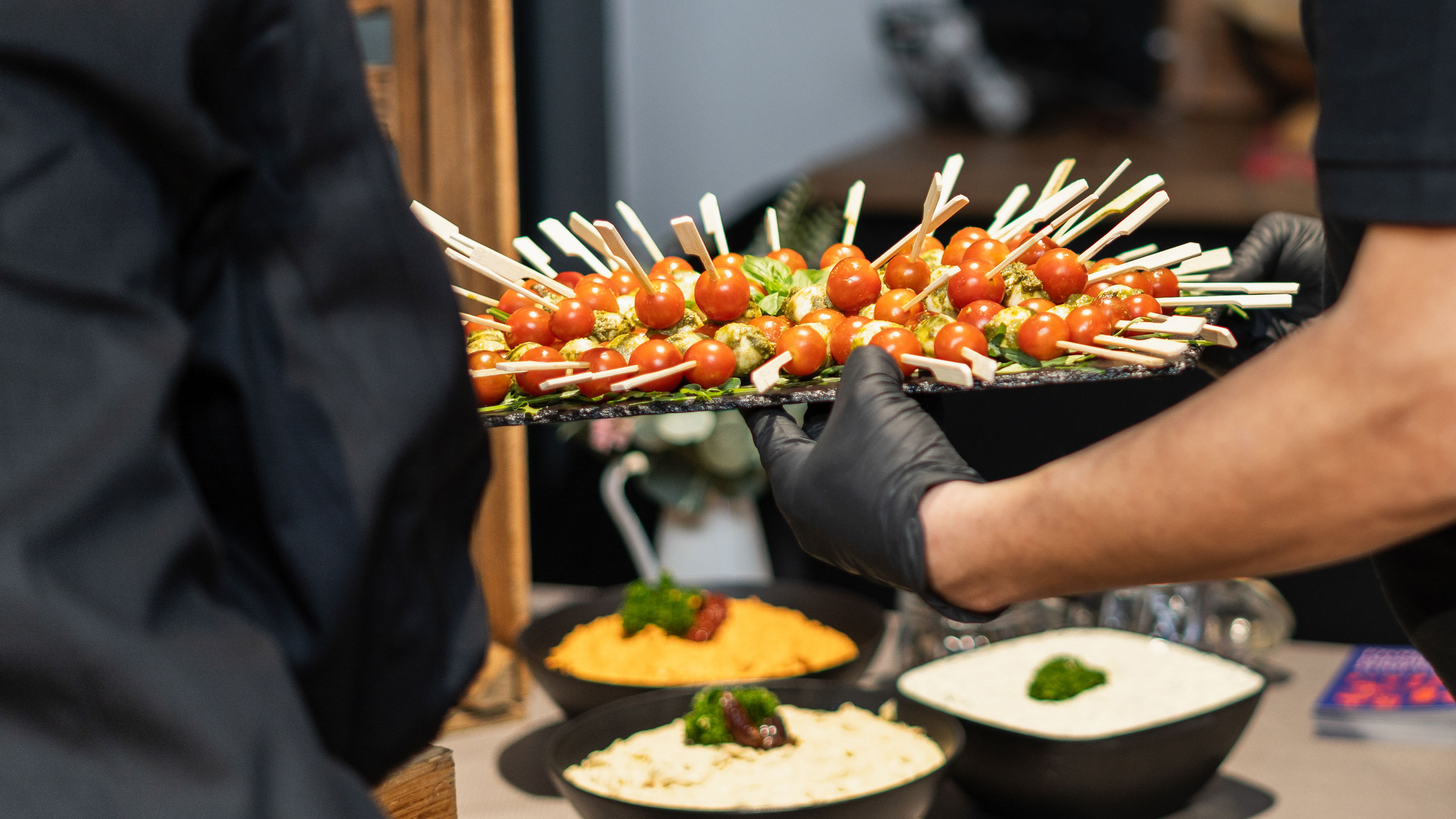Servicekraft reicht ein Tablett mit Caprese-Spießen bei einem EGS-Event