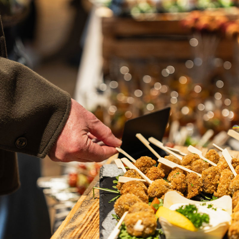 Gast greift bei einer Firmenfeier nach Fingerfood vom Buffet