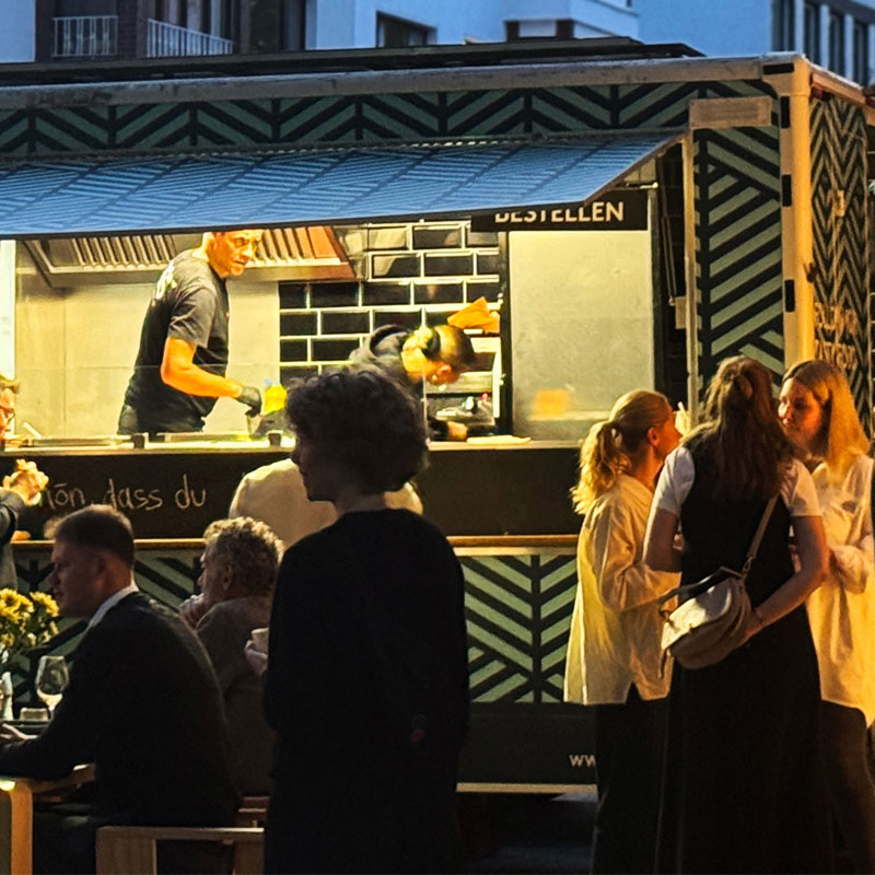 Food Truck am Abend mit wartenden Gästen davor