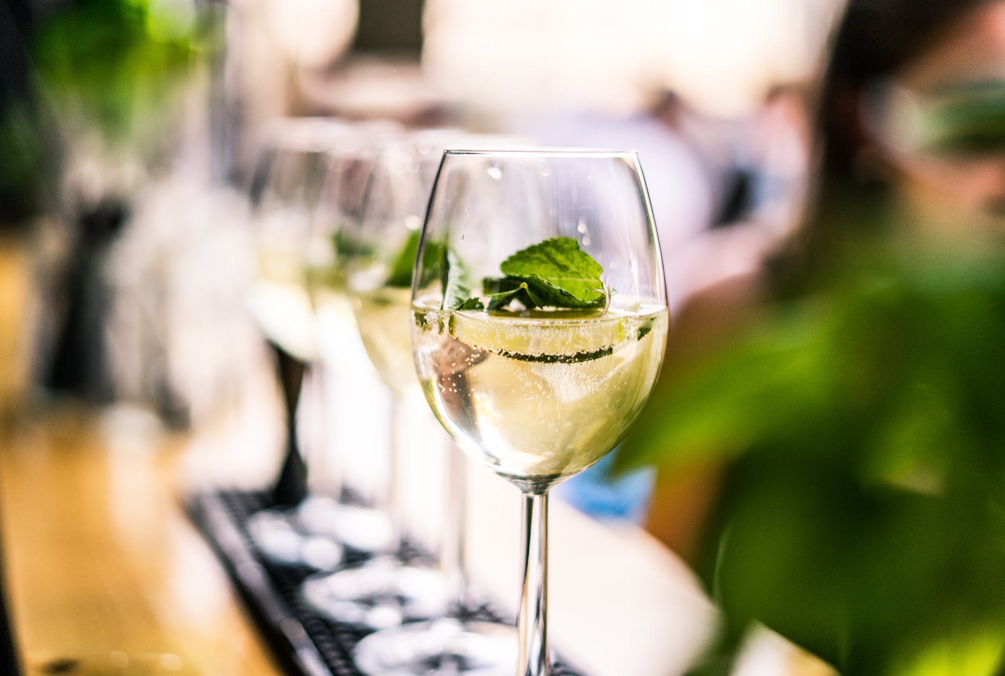 Aufgereihte Weingläser mit Minze und Eiswürfeln an der Bar