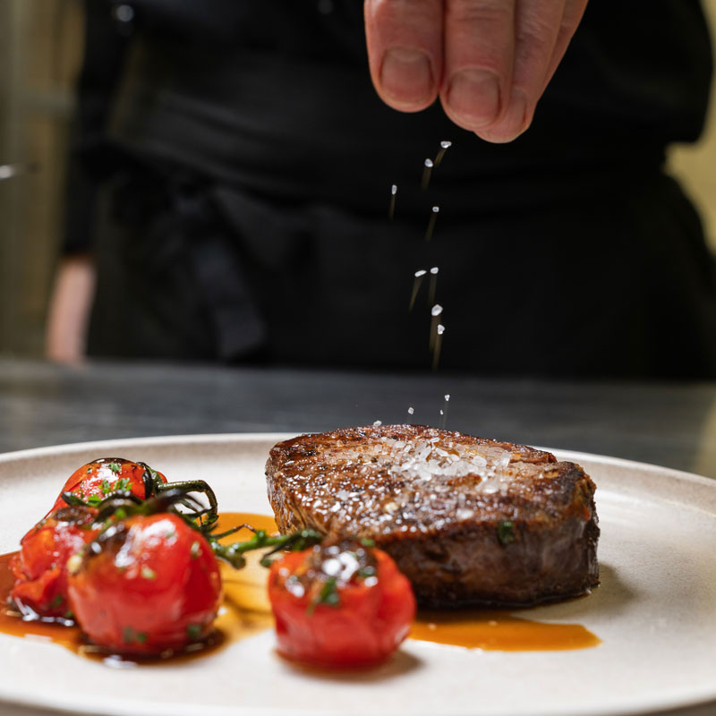 Angerichtetes Steak mit gebackenen Tomaten auf einem Teller