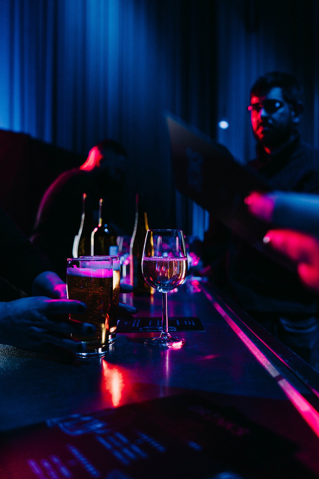 Bar mit Bier- und Weingläsern bei einem Abendevent, im Hintergrund das Serviceteam